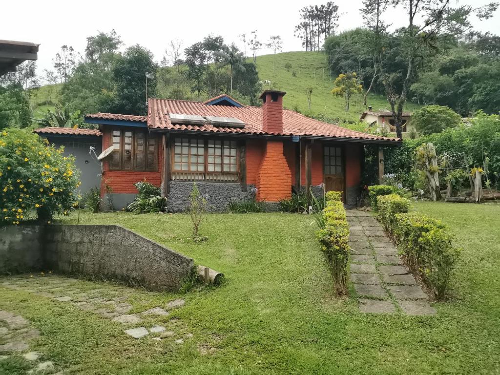 a house in the middle of a green yard at Chalé Mauá Conforto e Arte in Visconde De Maua
