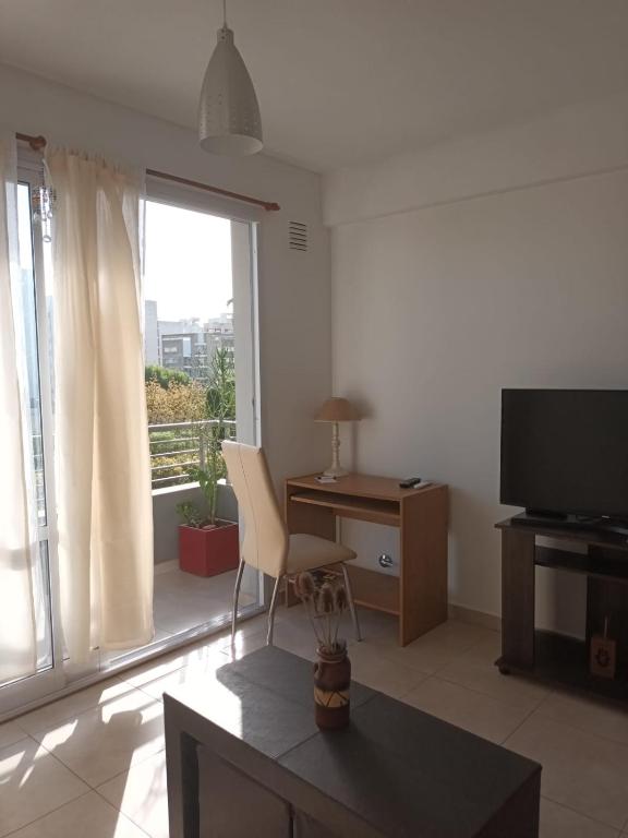 a living room with a television and a desk and a window at DEPTO 2 Y 62 CON COCHERA PROPIA in La Plata