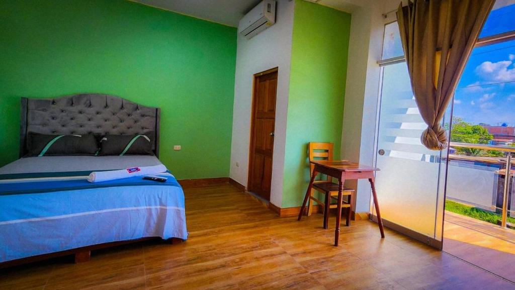 Hotel LUCHINE في بوكالبا: غرفة نوم بجدران خضراء وسرير وطاولة