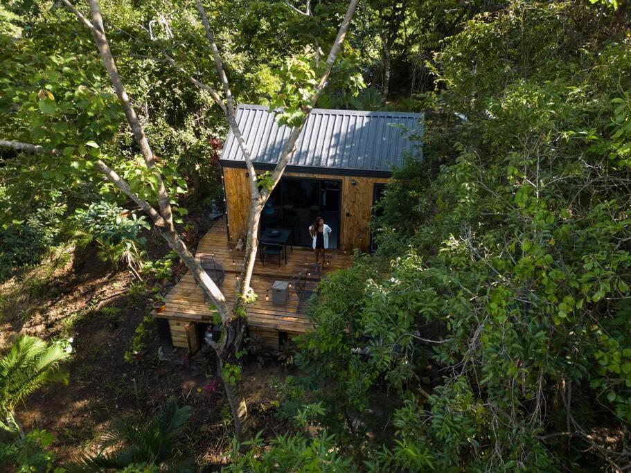 una cabaña en el bosque con una persona de pie en una terraza de madera en Kooteja Kätalina, 
