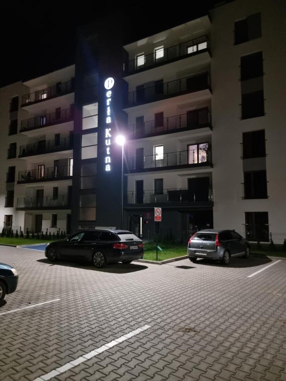 dos autos estacionados en un estacionamiento frente a un edificio en Perłowy Apartament, en Kutno