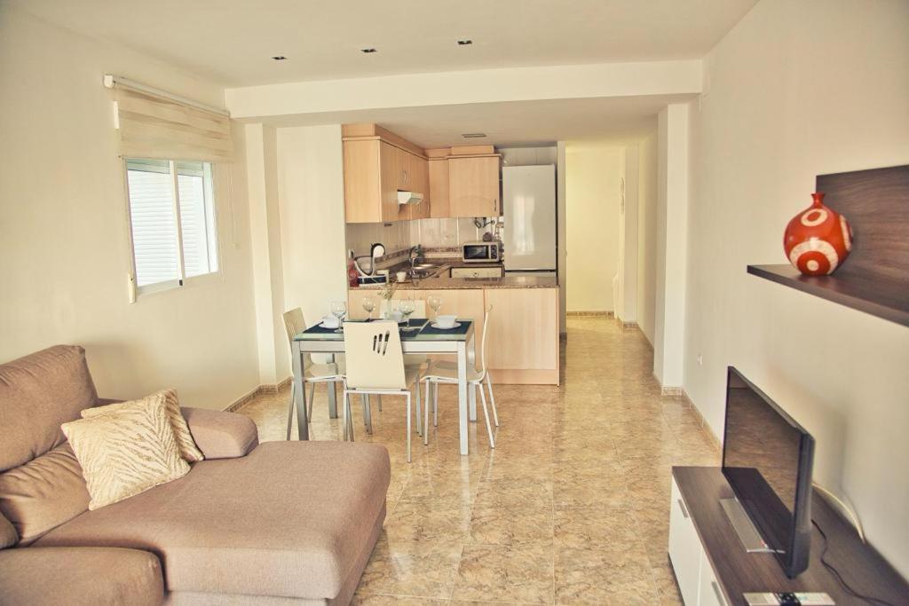 een woonkamer met een bank en een tafel en een keuken bij Apartamento Playa Xilxes in Xilxes