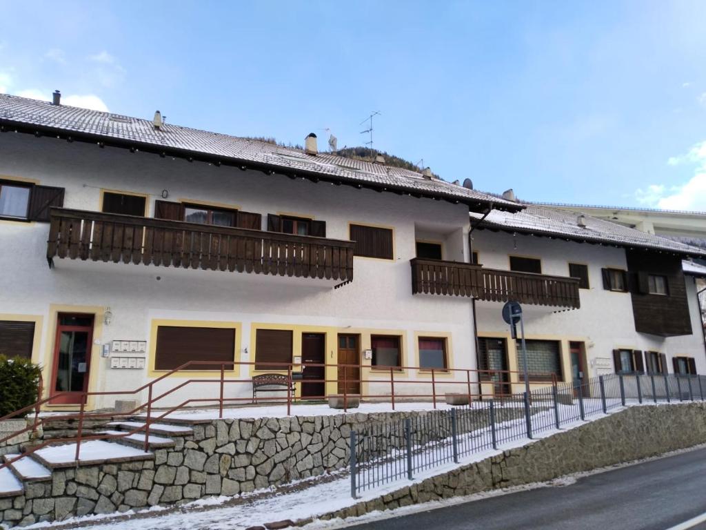 un edificio blanco con balcones de madera en un lateral en A Casa Dei - Appartamento Colle Isarco, en Colle Isarco