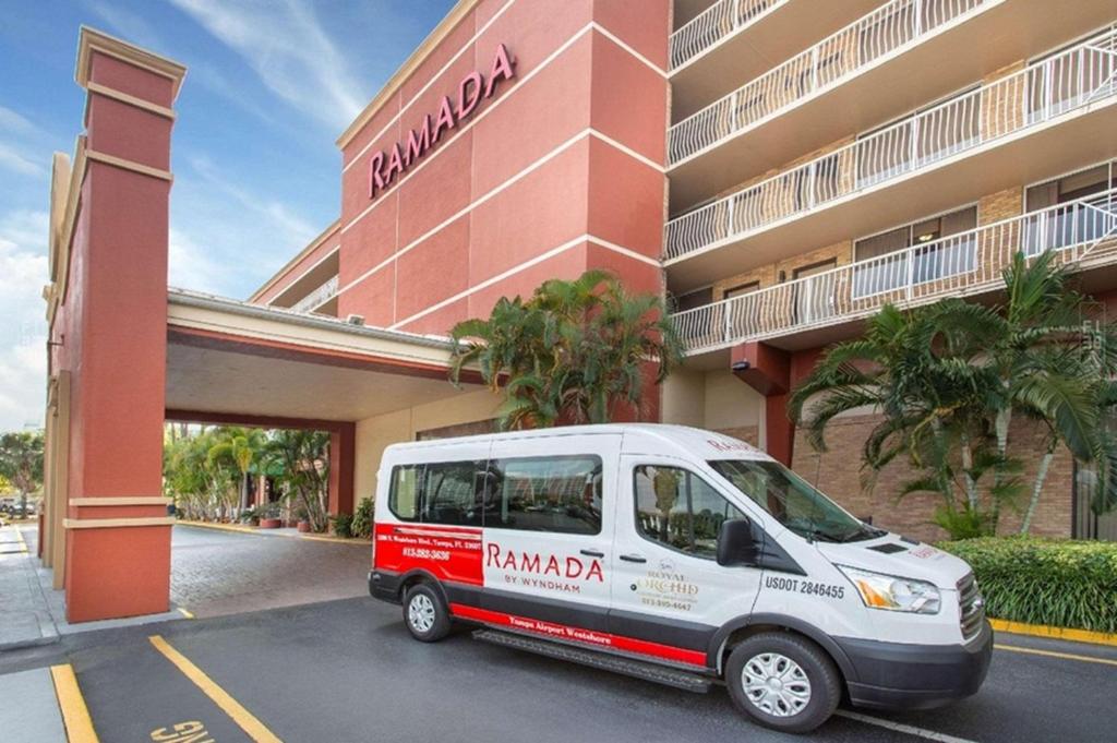 Ramada by Wyndham Tampa Westshore Airport South في تامبا: سيارة فان بيضاء متوقفة أمام مبنى