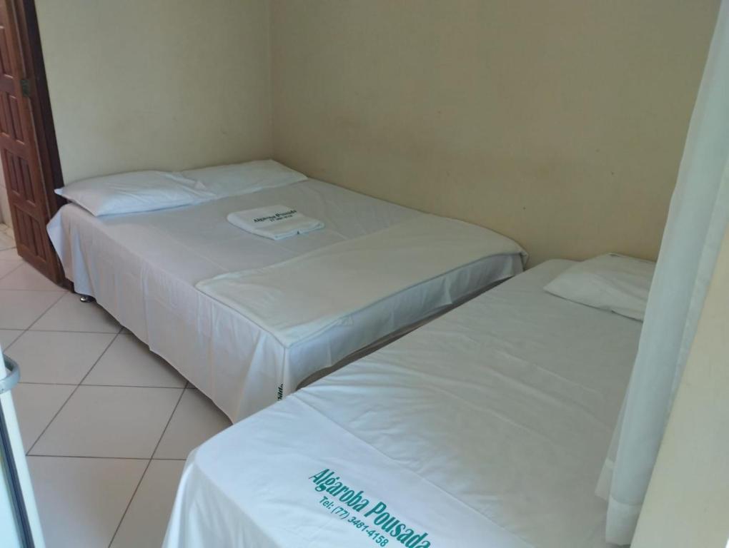 2 camas en una habitación pequeña con sábanas blancas en Hotel Algaroba Anexo, en Bom Jesus da Lapa
