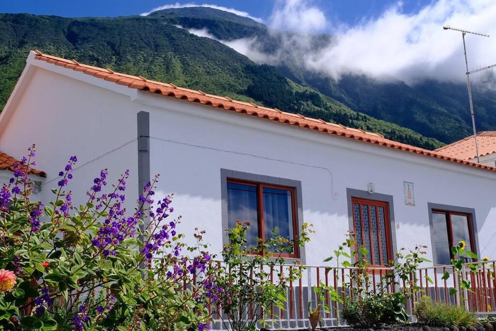 une maison blanche avec des montagnes en arrière-plan dans l'établissement Sunflower Guest House - Pico, à São Caetano