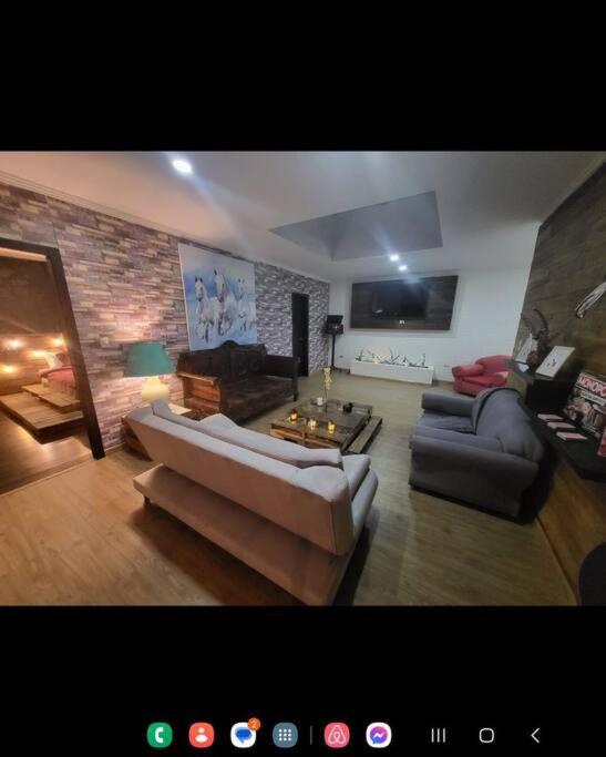 ein Wohnzimmer mit 2 Sofas und einer Ziegelwand in der Unterkunft CUENCA hermosa casa en el campo in Guishil