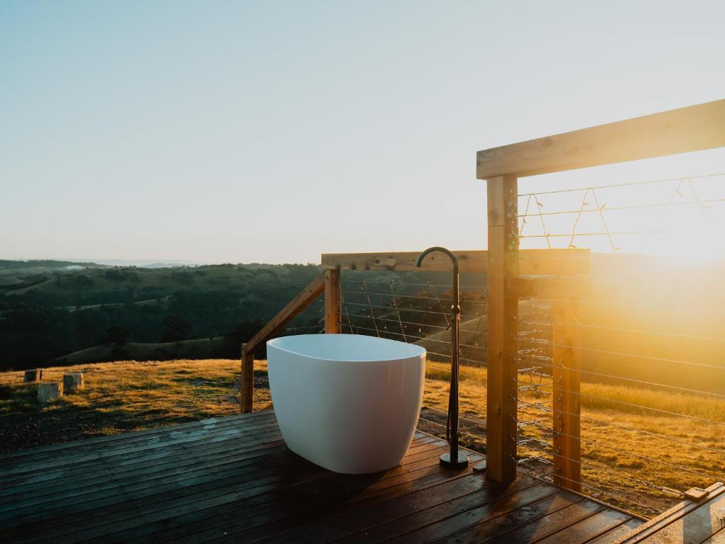 une baignoire assise sur une terrasse avec vue sur le coucher du soleil dans l'établissement Hilltop Off Grid Tiny House with Outdoor Bath, 