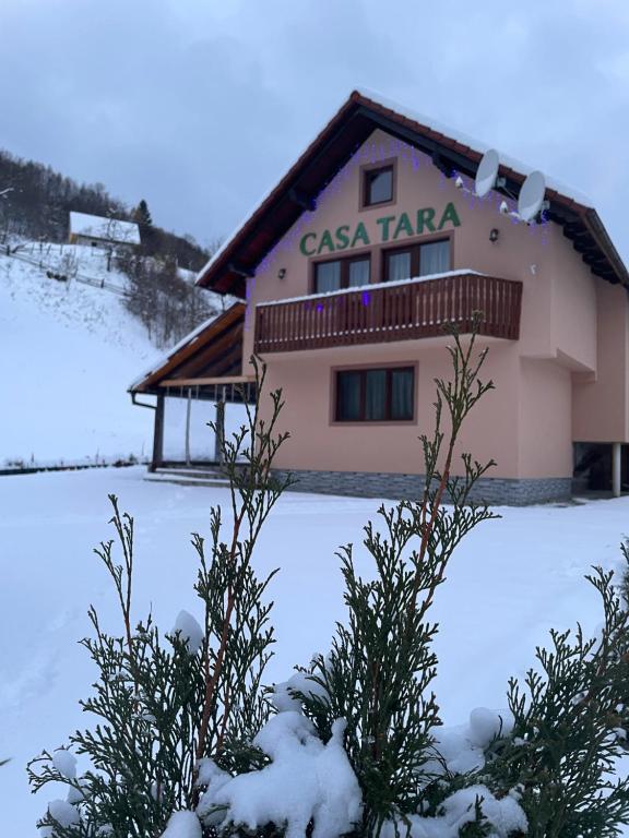 a house in the snow with trees in front at Casa de vacanța Tara in Rau Sadului