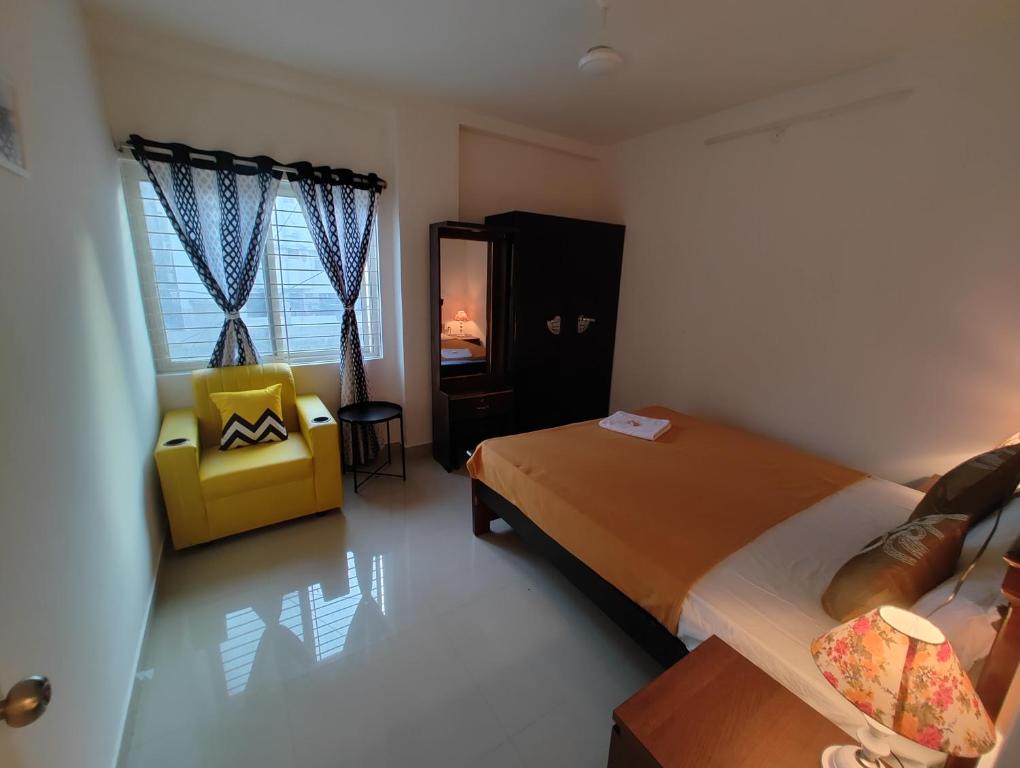 NK Homes - Serviced Apartments في حيدر أباد: غرفة نوم بسرير وكرسي اصفر