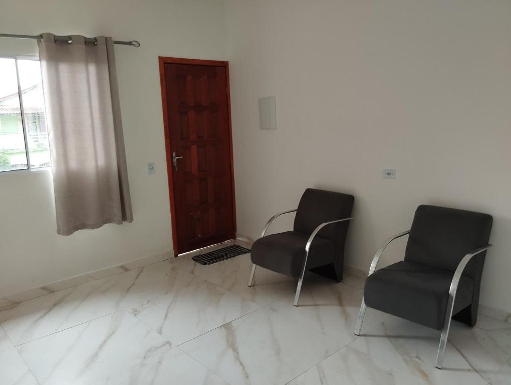 2 Stühle in einem Zimmer mit Tür in der Unterkunft LOCAMAR in Itanhaém
