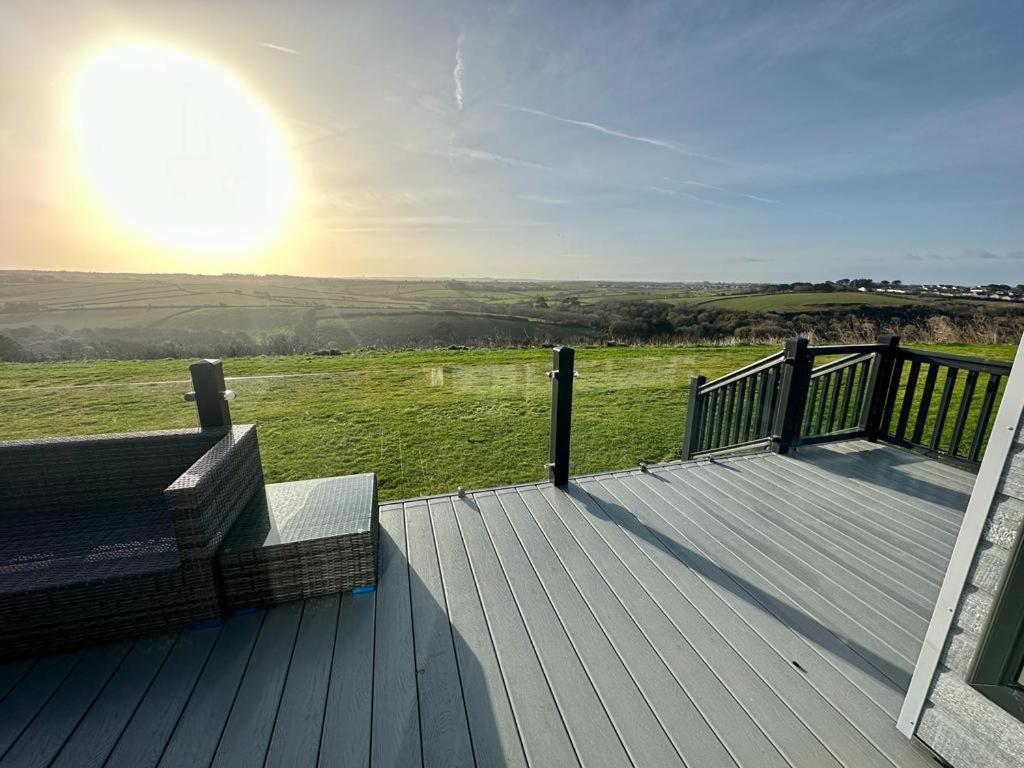 a wooden deck with a bench on top of a field at Luxury 3 bedroom Maple View Lodge, Newquay, Cornwall in Newquay