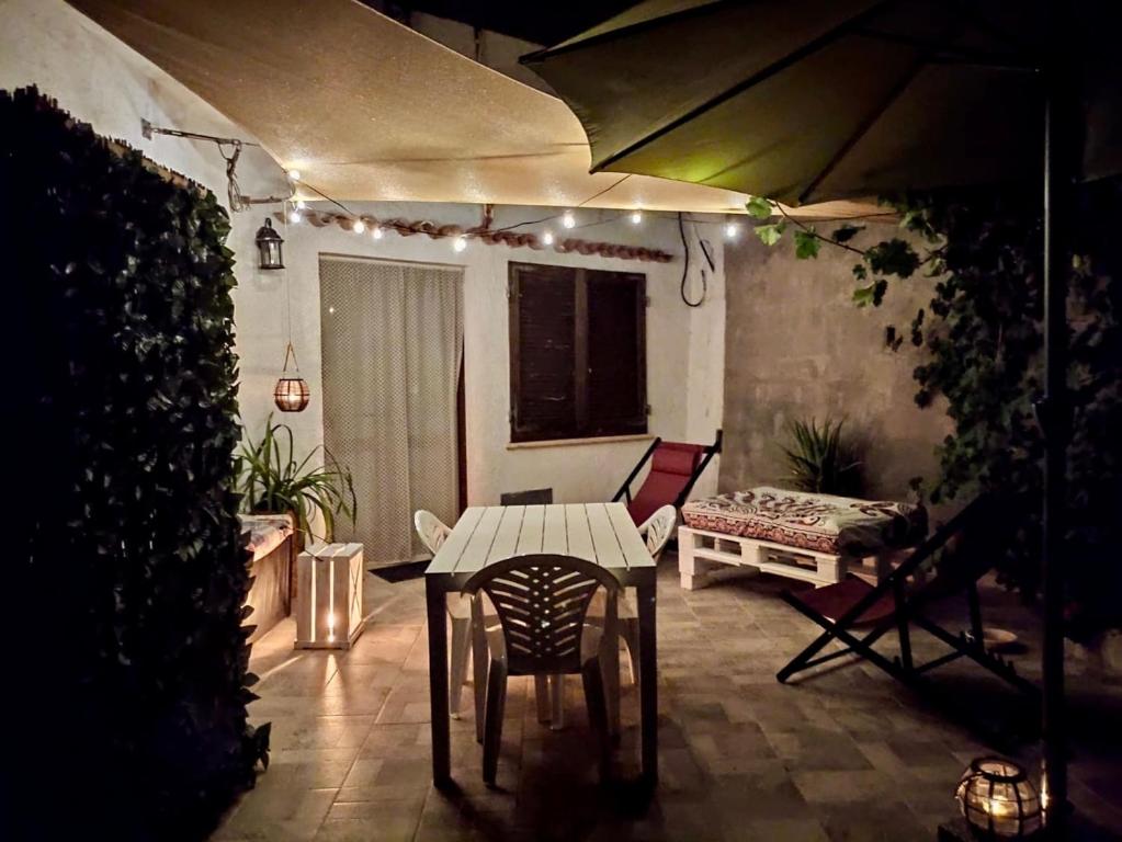 un patio con una mesa, un banco y luces en Il Melograno, en Badesi