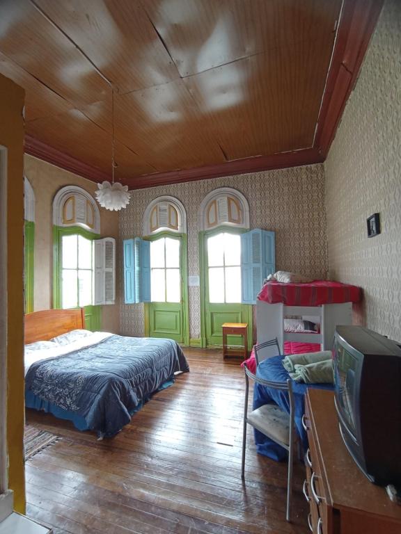 1 dormitorio con 1 cama y TV. en Hostal del gato en Valparaíso