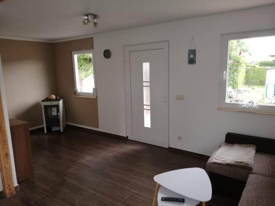 ein leeres Wohnzimmer mit Sofa und Fenstern in der Unterkunft Ferienwohnung am Stettiner Haff in Mönkebude