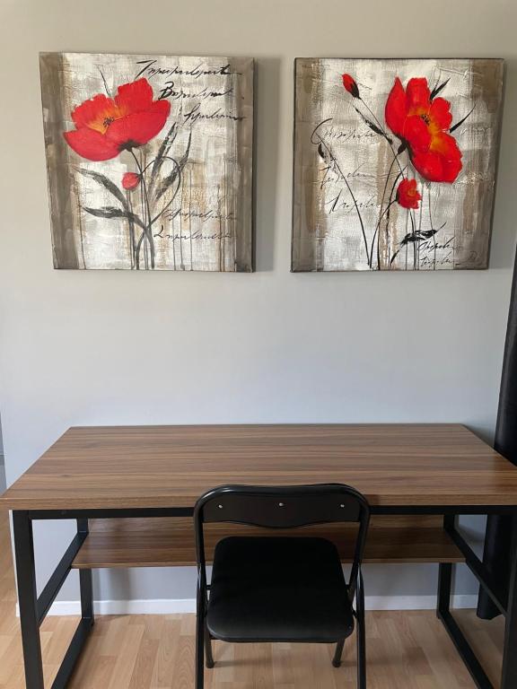 a wooden table with a chair in front of two paintings at Maison Carofanne in Saint-Siméon