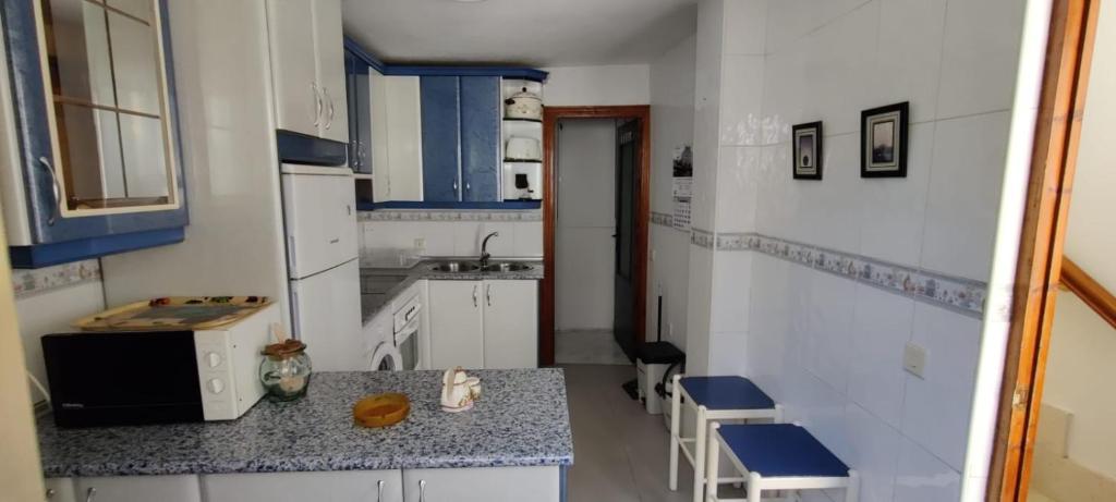 een kleine keuken met witte kasten en blauwe accenten bij Casa El Rostro in Aldeadávila de la Ribera