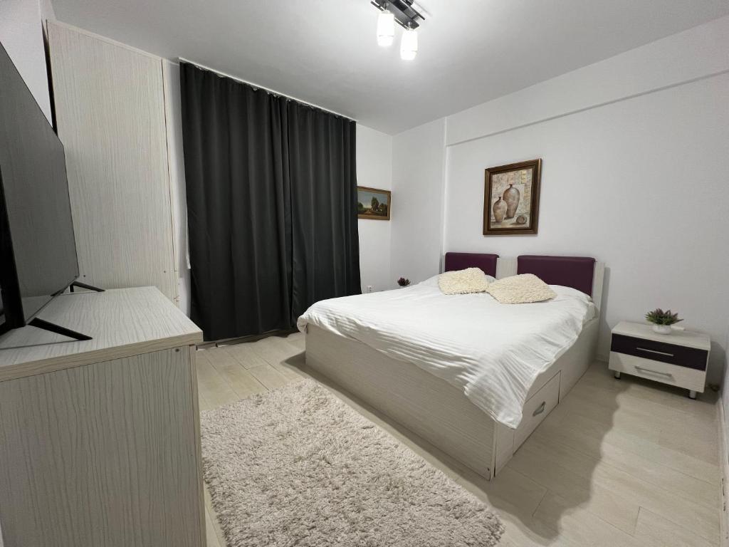 1 dormitorio con 1 cama blanca y TV en Apartament Bragadiru complex rezidențial en Bragadiru