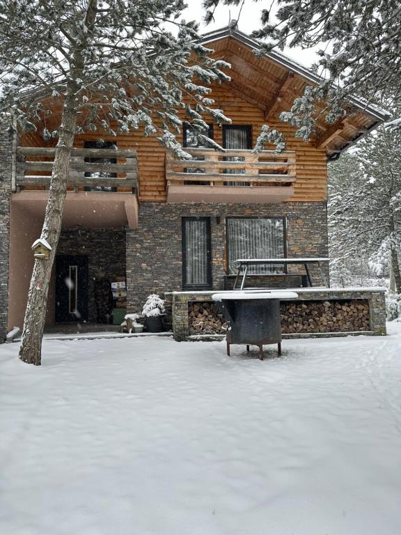 une maison avec une table dans la neige devant elle dans l'établissement Snježna vikendica, à Risovac