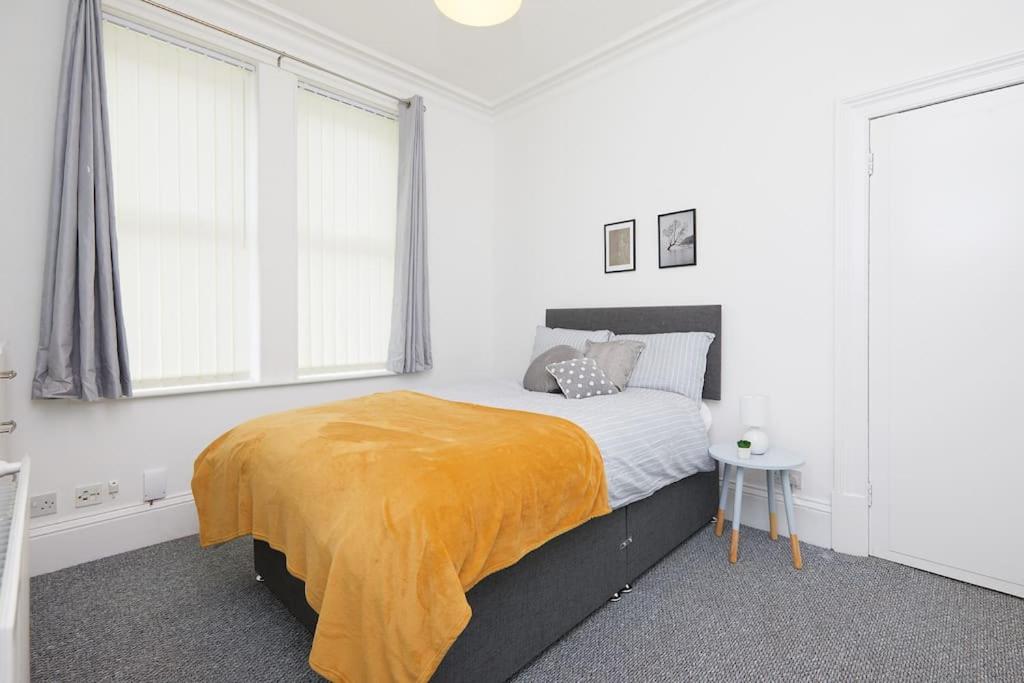 a bedroom with a bed with a yellow blanket on it at Derby central 4 bed house - Free parking in Derby