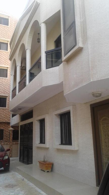 un bâtiment avec un balcon et une voiture garée à l'extérieur dans l'établissement CHEZ TAHIROU Birfy, à Fatick