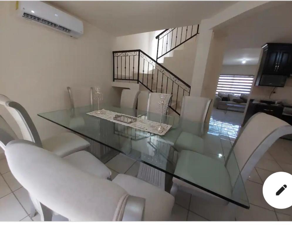 a dining room with a glass table and white chairs at Casa con alberca compartida Netflix Disney + Amazon TV in Hermosillo