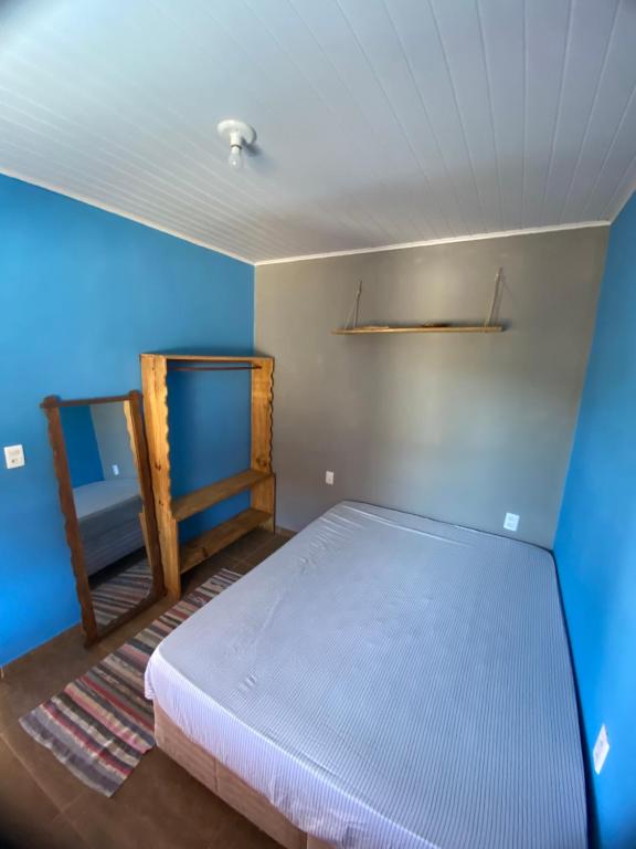 um quarto com uma cama e uma parede azul em Vila mágica hospedagem em Itaúnas