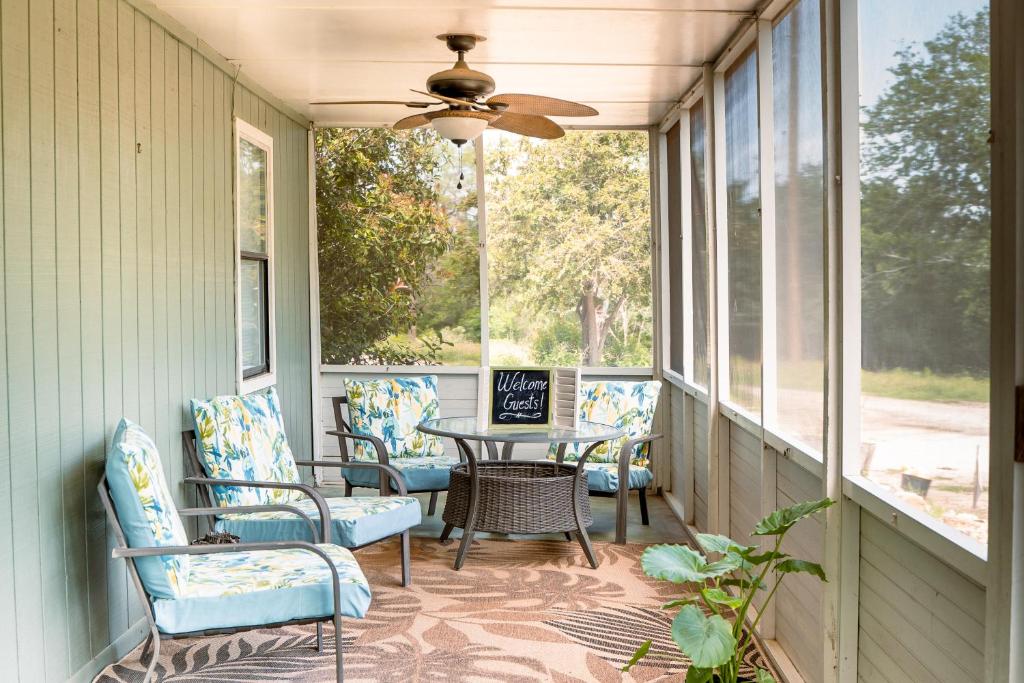 eine Veranda mit Stühlen, einem Tisch und einem Deckenventilator in der Unterkunft Hadley's House - A Country 3 Bdrm with Screened-In Porch in New Braunfels