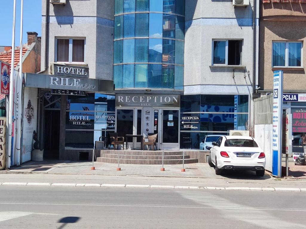a white car parked in front of a building at Hotel Rile Men Blue in Niš