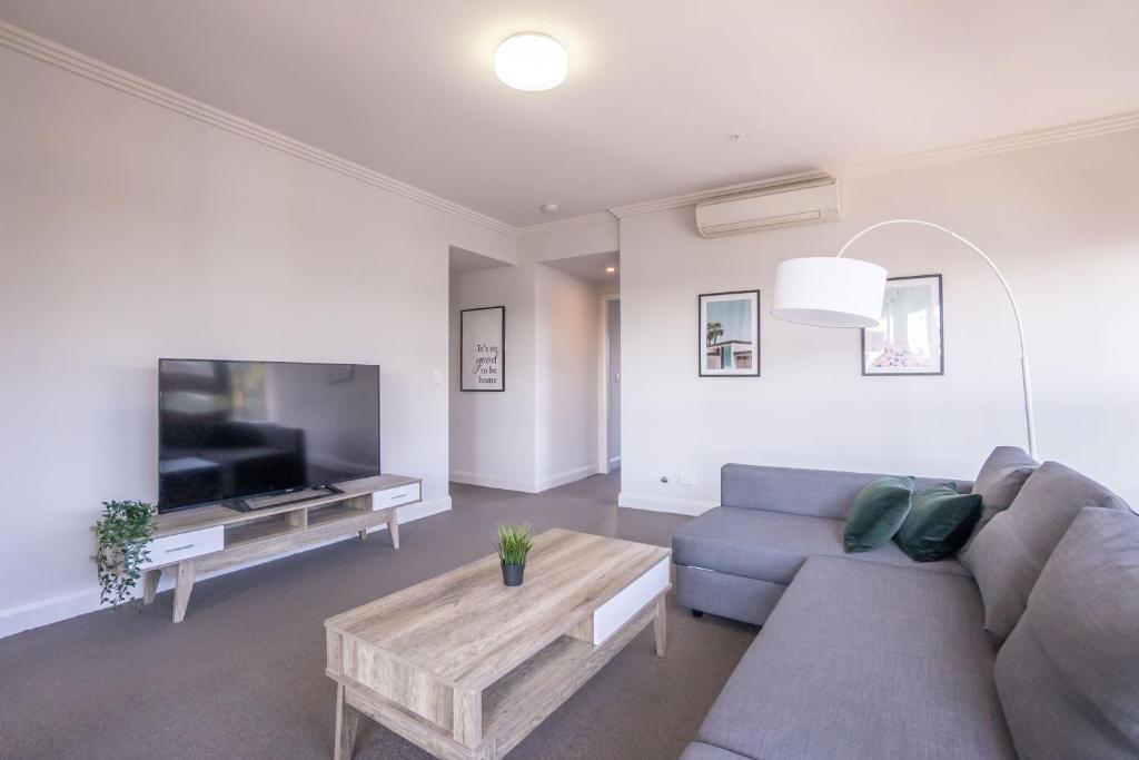 uma sala de estar com um sofá, uma mesa e uma televisão em Olympic Park 2 Bedrooms Charm Family Friend Free Parking em Sydney