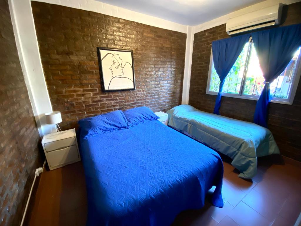 a bedroom with two beds and a brick wall at Hospedaje Noah in Ezeiza