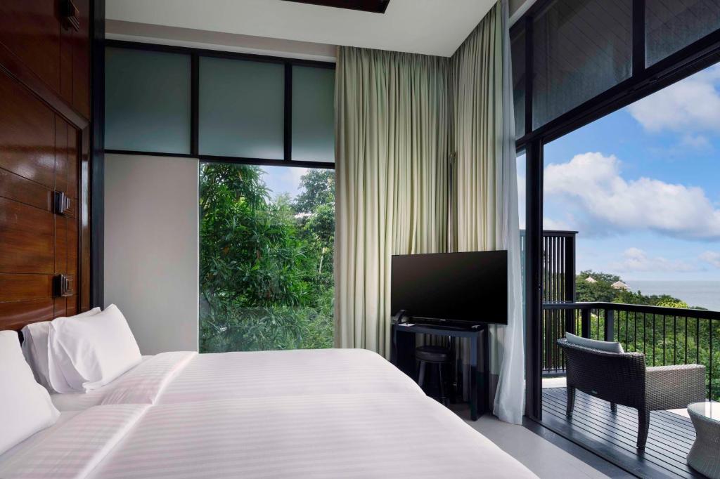 a bedroom with a bed and a balcony with a television at Banyan Tree Samui in Lamai