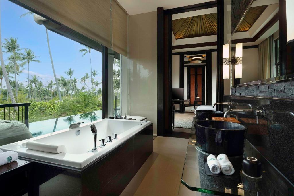 a bathroom with a large bath tub with a large window at Banyan Tree Samui in Lamai