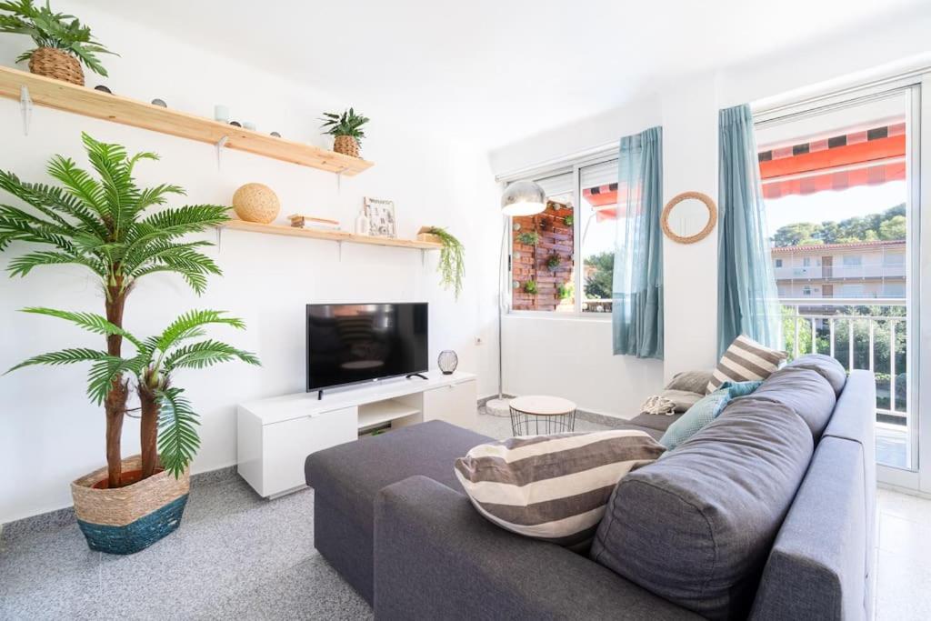 a living room with a couch and a palm tree at Privilegiado-Tarragona-50mPlaya-WIFI-Pool-Relax8 in Tarragona