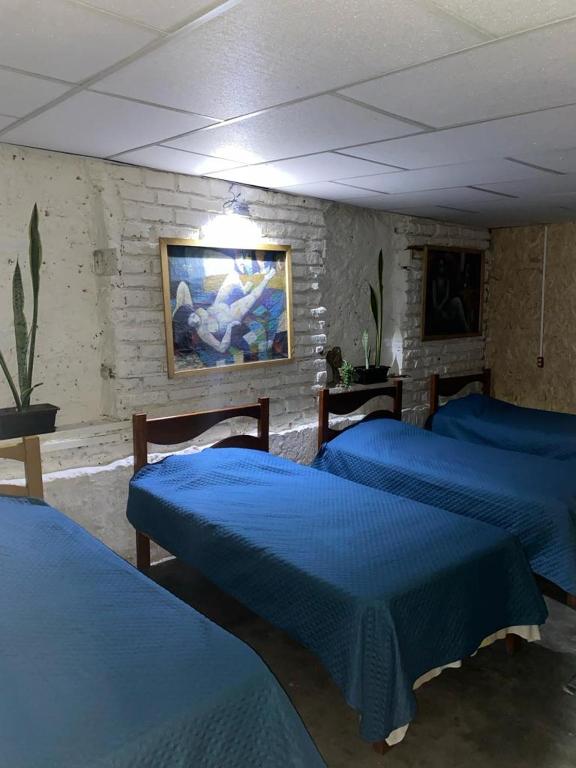 a room with three beds and a painting on the wall at Enkanta Guest House in Trujillo