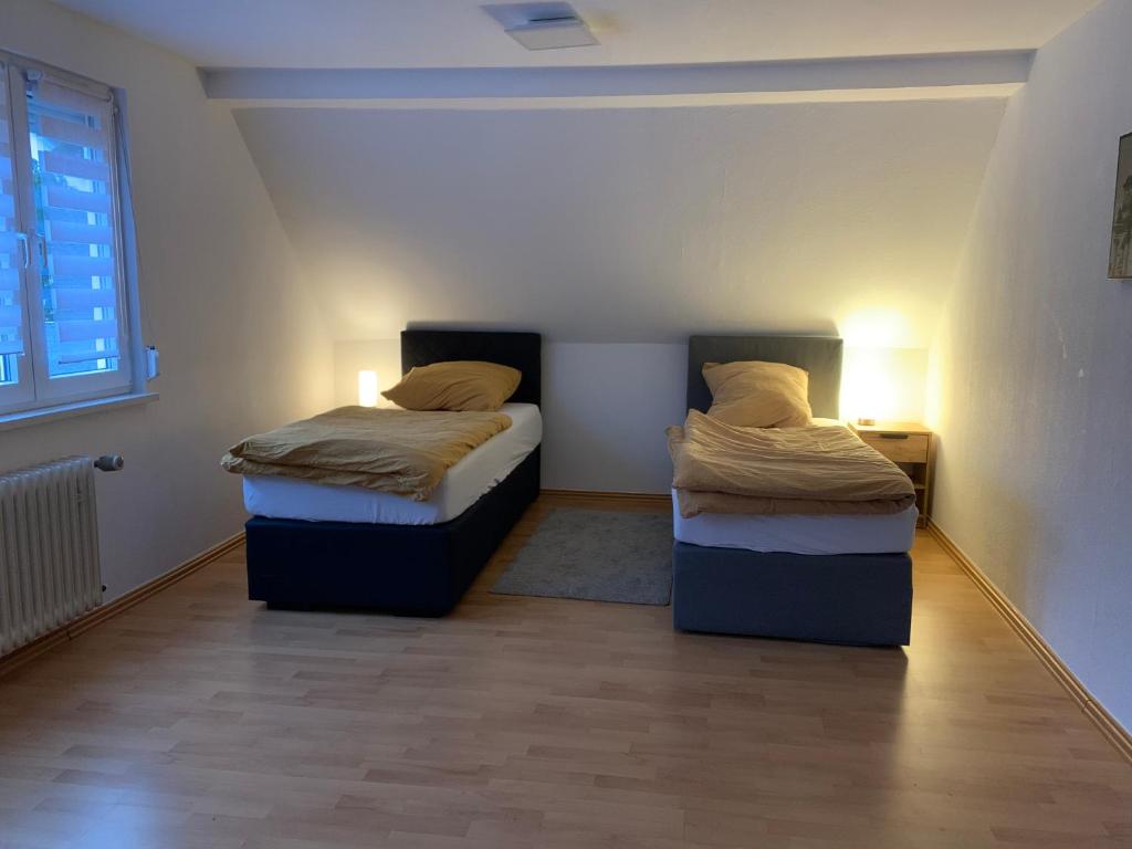 two beds in a small room with two lamps at Ferienwohnung Herborn in Herborn