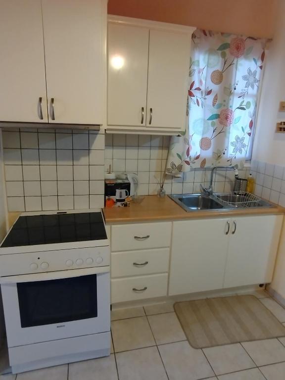 a kitchen with white cabinets and a sink at Evi's house in Nikiana