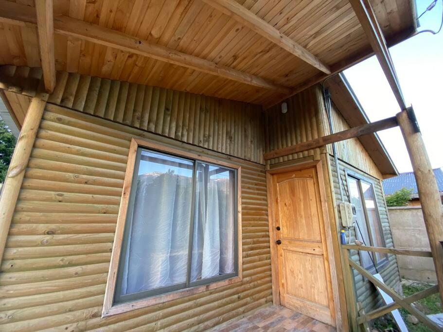 a wooden house with a window and a door at Cabaña en sector residencial in Puerto Aisén