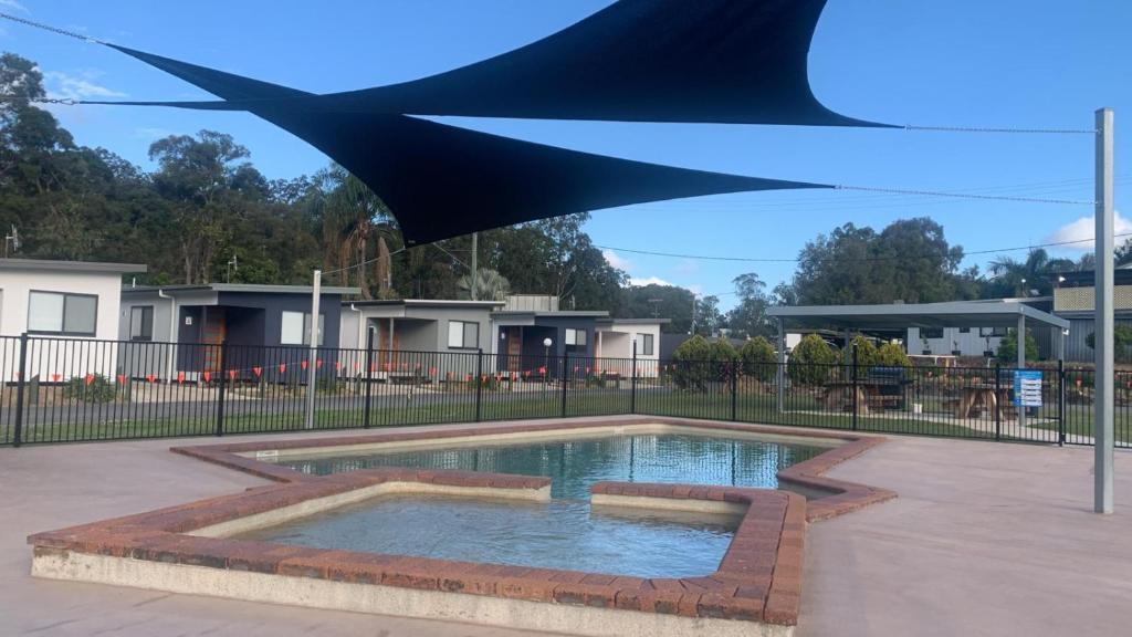 a swimming pool with a blue umbrella over it at Yandina Caravan Park in Yandina