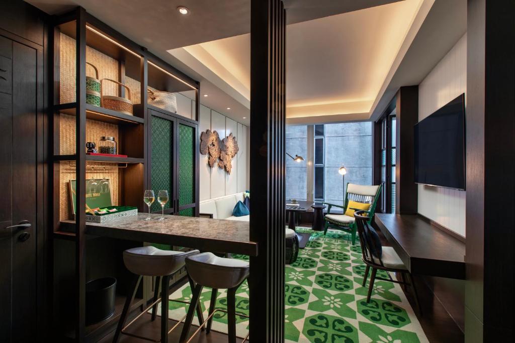 An open-plan room with a compact bar, dining counter, desk, and lounge seating.