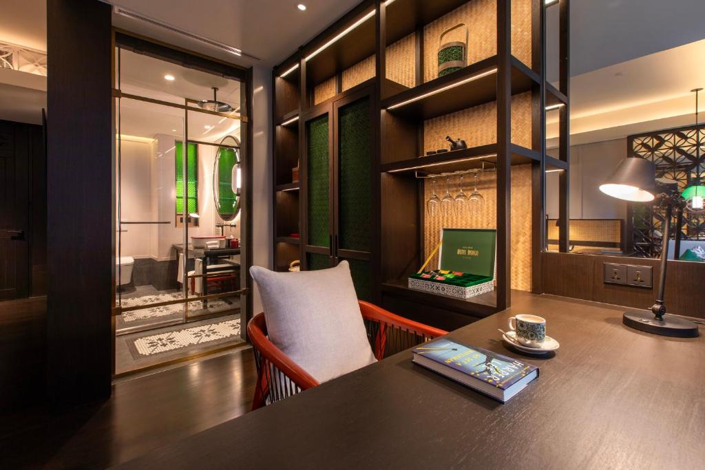 A dedicated desk beside open shelving, with a chair and a view toward the bathroom and lounge.