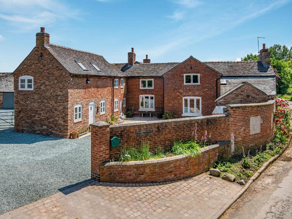 une grande maison en briques avec un mur en briques dans l'établissement Northwood Farm Cottage, à Marchamley
