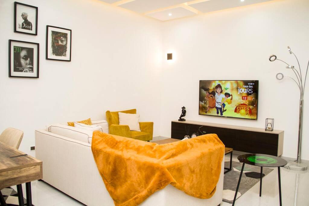 a living room with a couch and a tv on a wall at Luxueux Appartement meublé à Cotonou in Cotonou