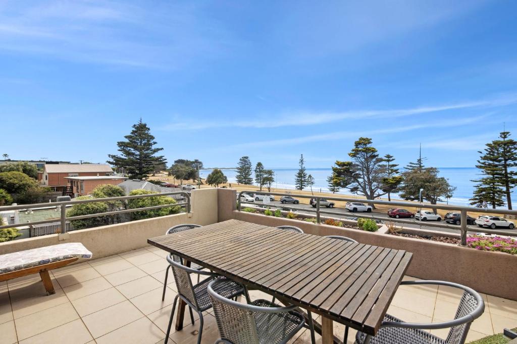 a table and chairs on a balcony with a view of a highway at Esplanade Absolute Beach Frontage 12-20 in Torquay