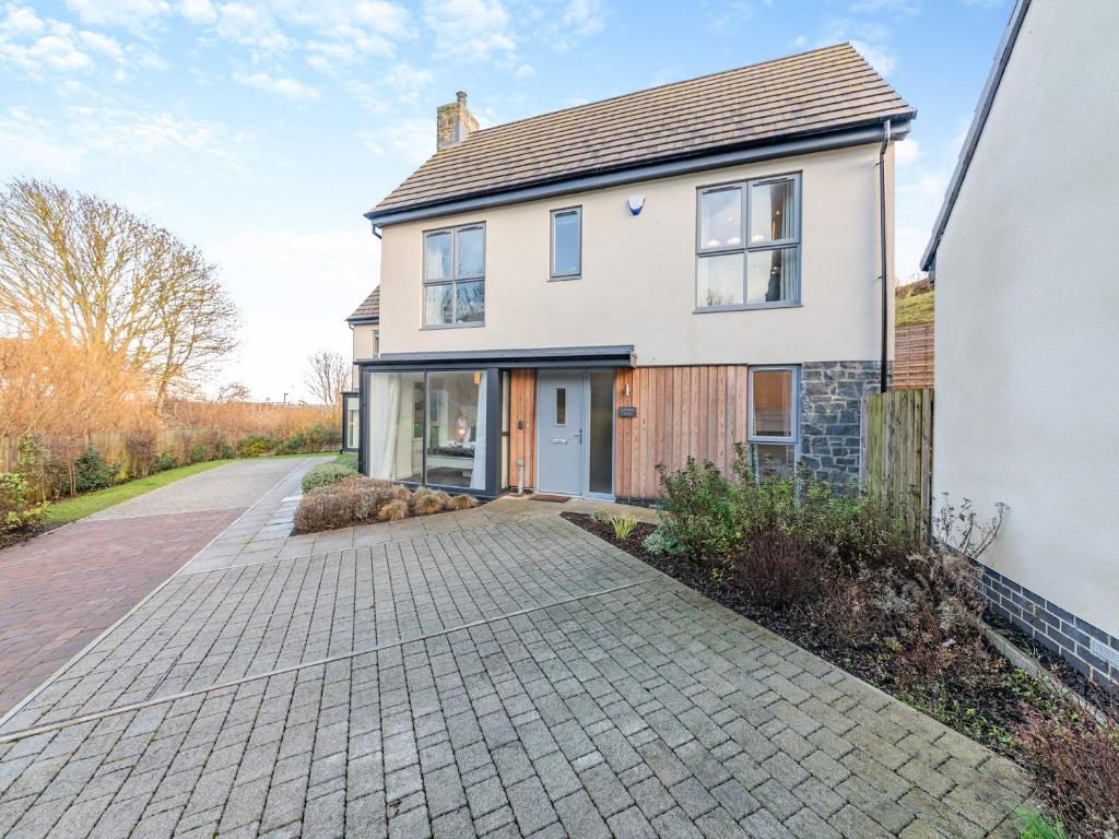 een wit huis met een geplaveide oprit bij Whinstone House in Craster