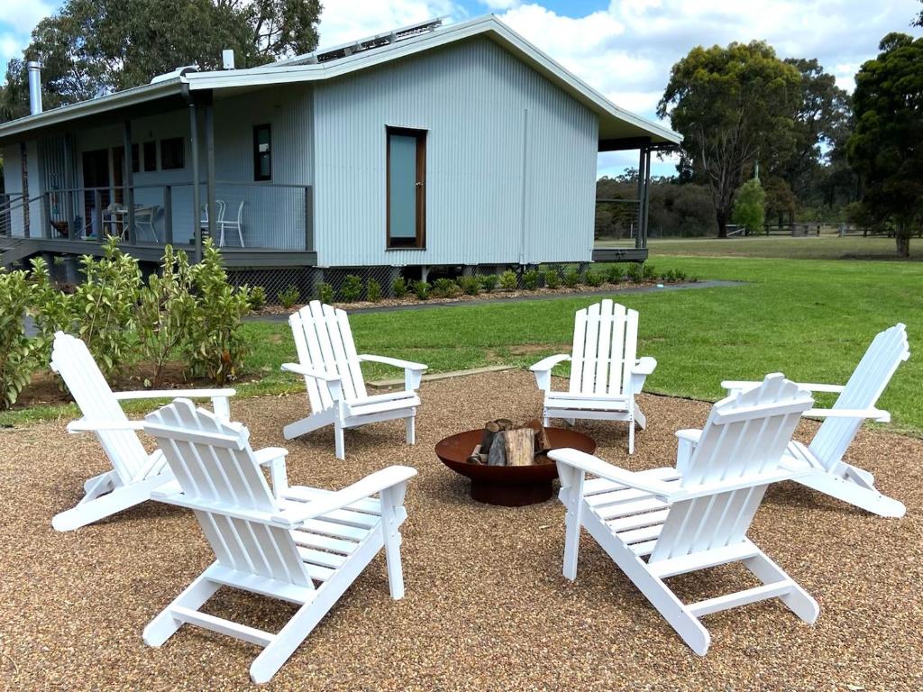 4 chaises blanches et un foyer extérieur en face d'une maison dans l'établissement Hannah's Place in the heart of Lovedale, Hunter Valley wine country, Free bottle of wine with each booking, à Lovedale