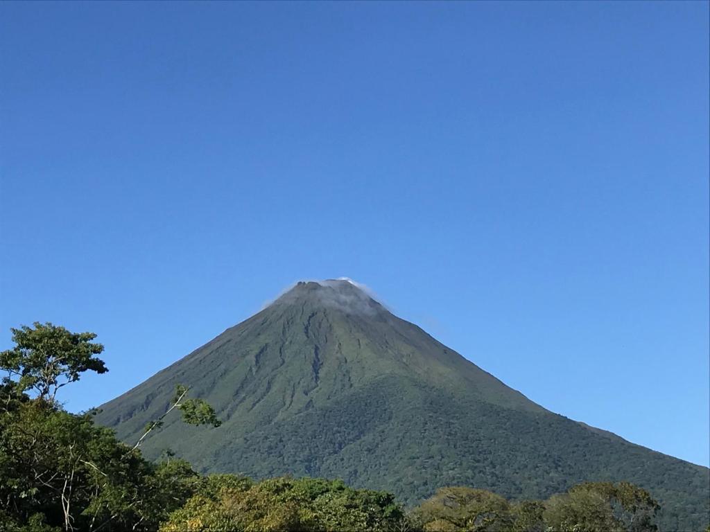 a mountain with trees in front of a blue sky at Arenal Monara in Fortuna