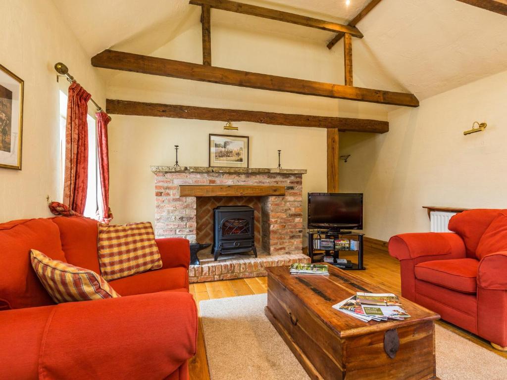 a living room with red furniture and a fireplace at Anvil Cottage in Biscathorpe