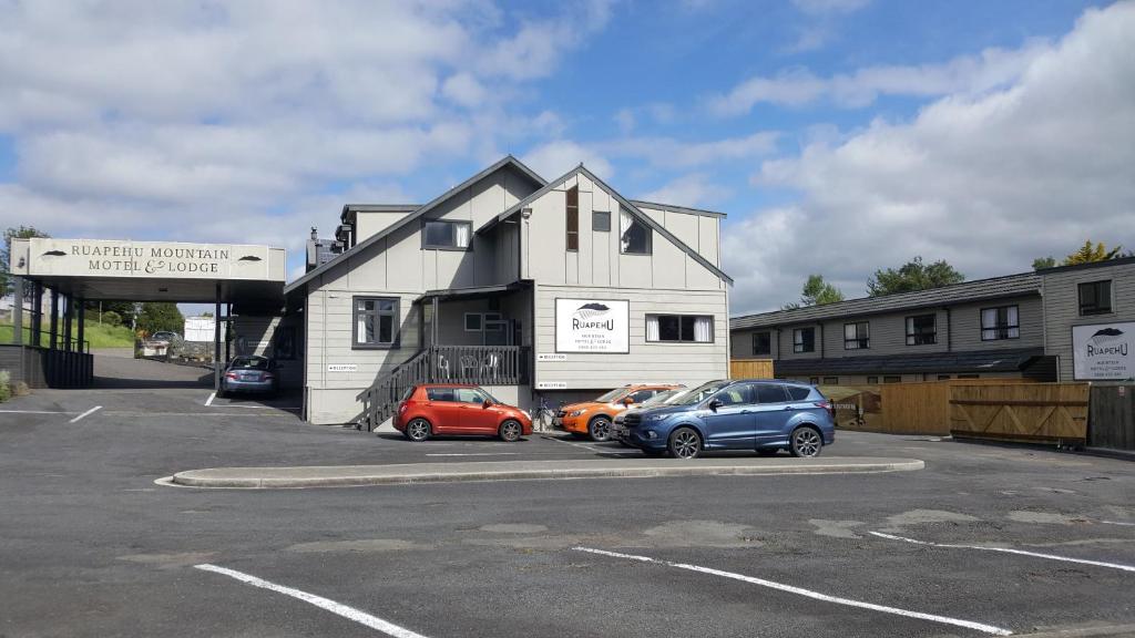 tres autos estacionados en un estacionamiento frente a un edificio en Ruapehu Mountain Motel & Lodge, en Ohakune