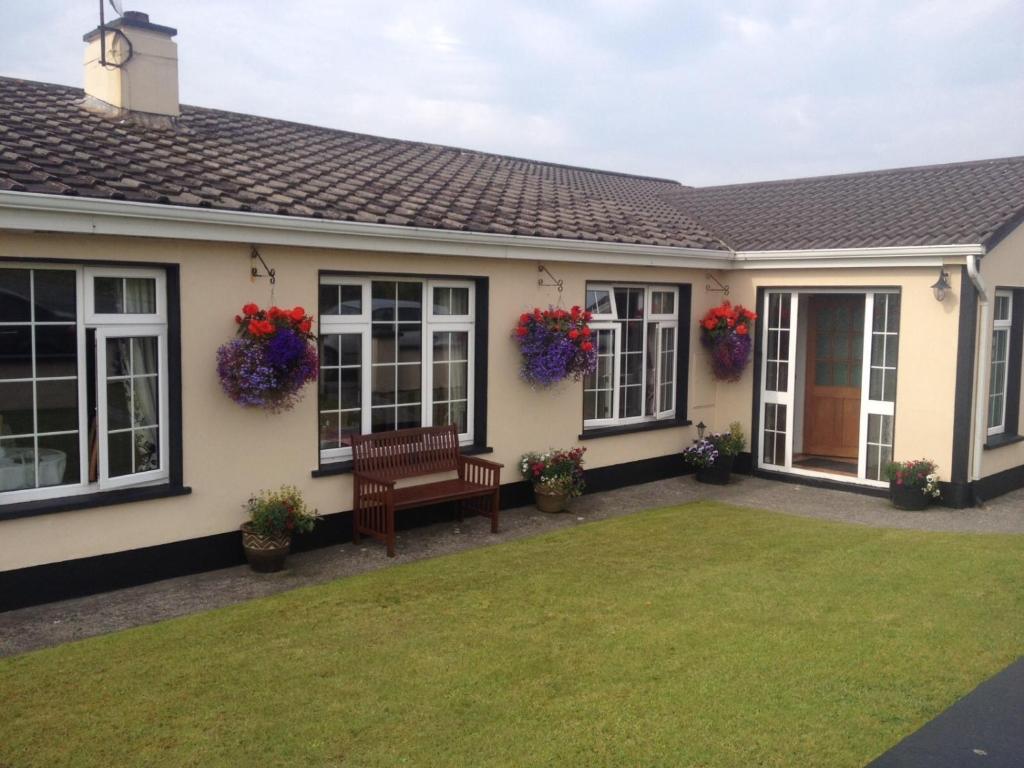 uma casa com flores nas janelas e um banco em Atlantic House em Lisdoonvarna